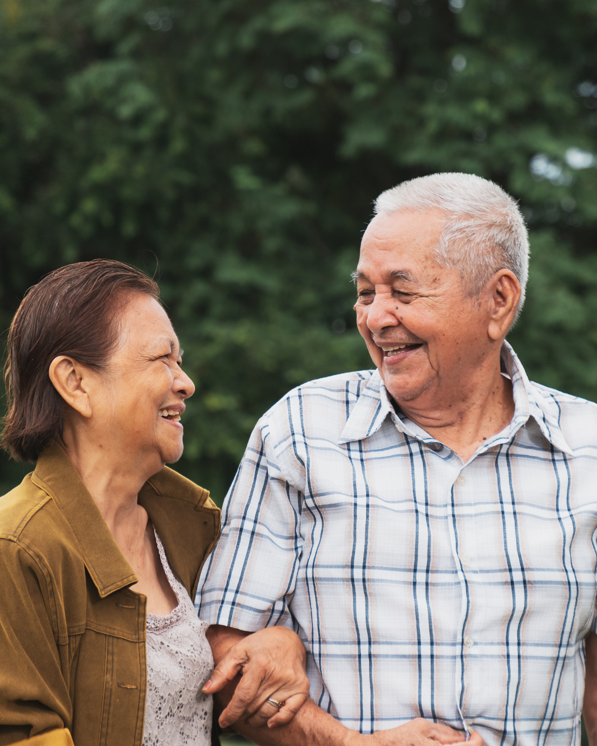 A smiling older couple laughing together outdoors